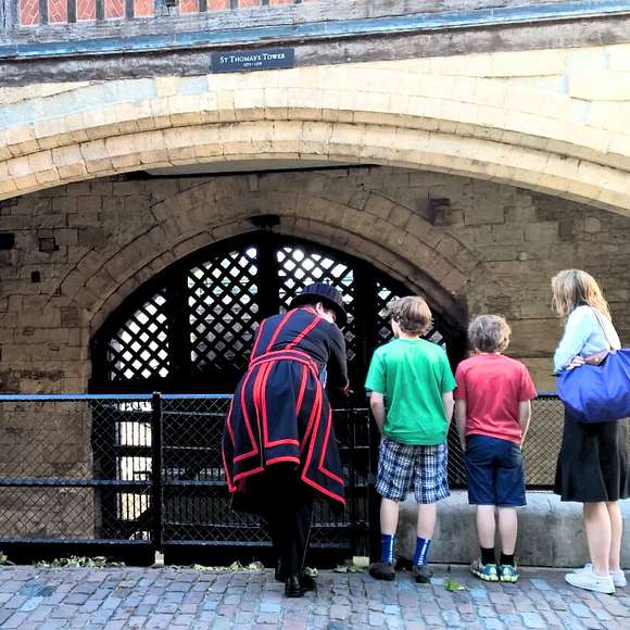 Beefeater guide speaking with a family of three in front of Traitor’s Gate at the Tower of London, under the arch of St Thomas’s Tower.